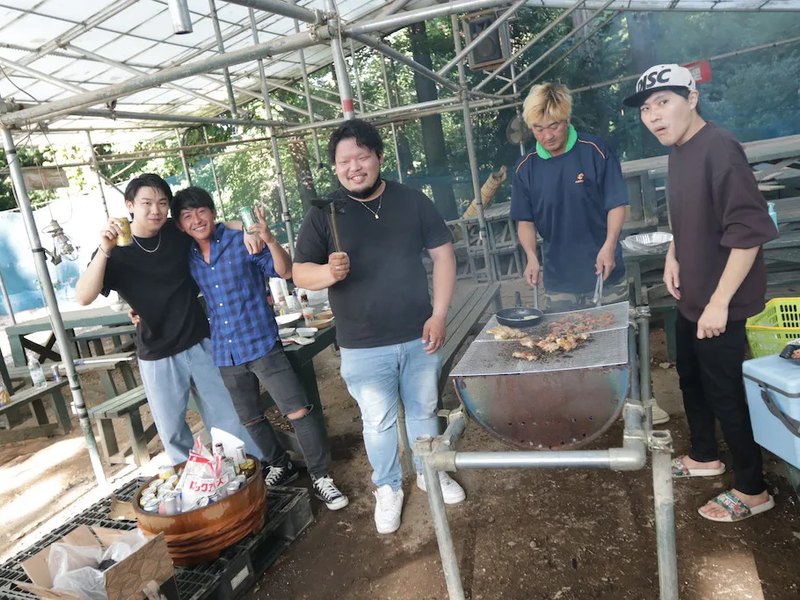 屋根付きのBBQエリアでコンロを囲む人たち